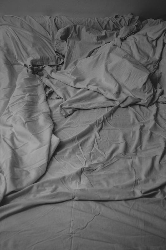 an unmade bed with a white comforter and sheets